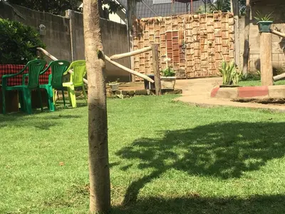a tree in a yard with chairs and a playground at Humphrey home stay in Arusha