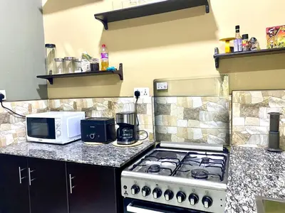 a kitchen with a stove and a microwave at Our Home your Home in Arusha in Nkoanrua