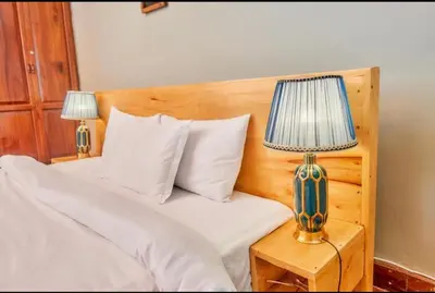 a bedroom with a bed with two lamps on a nightstand at Asante Home in Arusha