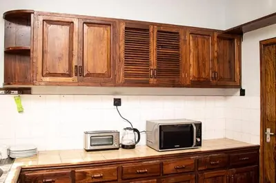 a kitchen with wooden cabinets and a microwave on a counter at Asante Home in Arusha
