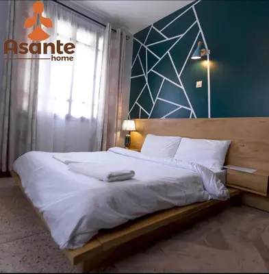 a bedroom with a large bed with a sign on the wall at Asante Home in Arusha