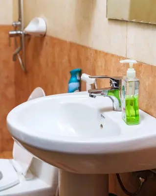 a bathroom sink with a green soap bottle on it at Arusha Urban Haven Homes - Amani Apartment in Arusha