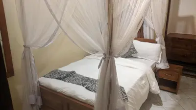 a bedroom with a canopy bed with white curtains at Ultra Home Hostel in Arusha