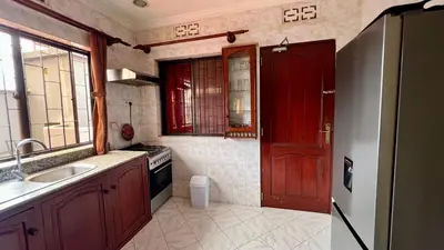 a kitchen with a sink and a red door at Ultra Home Hostel in Arusha