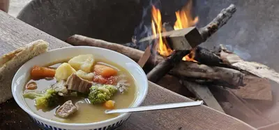 a bowl of soup in front of a fire at Shamba Pori Lodge in Idulo