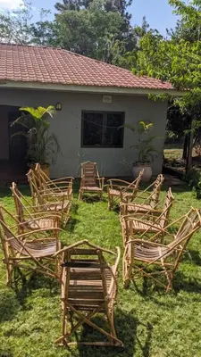 a group of chairs sitting in the grass in front of a house at Forest Side Homestay in Moshi