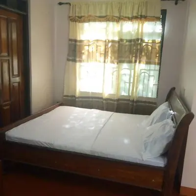 a bed sitting in a room with a window at Forest Side Homestay in Moshi
