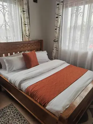 a bed with white and orange sheets and windows at \u86cb\u7092\u996d\u6c11\u5bbf in Samanga