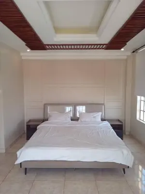 a bedroom with a large bed with white sheets and pillows at Cosy 2 bedroom apartment in Arusha