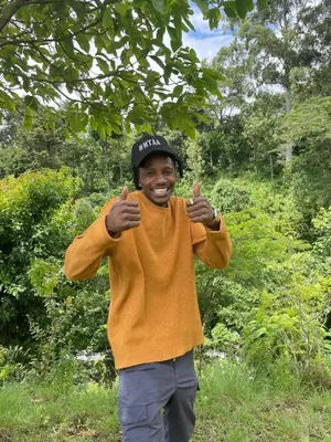 a man giving the thumbs up sign while standing under a tree at Mai Kilimanjaro Home Stay in Moshi