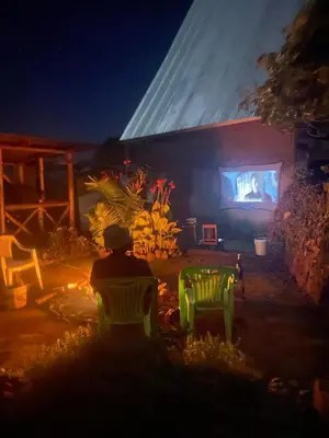 a person sitting in chairs watching a presentation on a stage at Mai Kilimanjaro Home Stay in Moshi