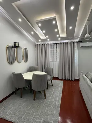 a dining room with a table and chairs and a couch at Aggiestays - Shanty Town Moshi in Moshi