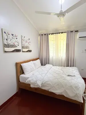 a bedroom with a bed with white sheets and a window at Aggiestays - Shanty Town Moshi in Moshi