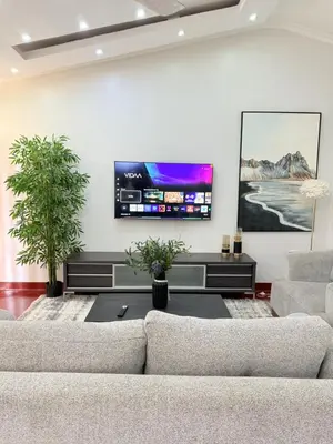 a living room with two couches and a flat screen tv at Aggiestays - Shanty Town Moshi in Moshi