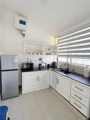 a kitchen with white cabinets and a white refrigerator at Aggiestays - Shanty Town Moshi in Moshi