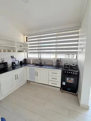 a kitchen with white cabinets and a black stove at Aggiestays - Shanty Town Moshi in Moshi