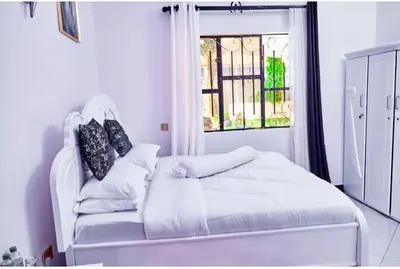 a white bed in a room with a window at Dema home in Arusha