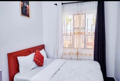 a bed with a red pillow in a room with a window at Dema home in Arusha