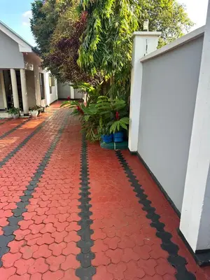 a red brick walkway with a white fence and plants at Dema home in Arusha