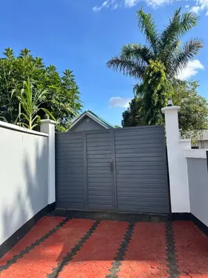 a gate in a fence with a palm tree in the background at Dema home in Arusha