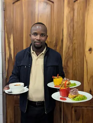 a man is holding two plates of food at Mvuli Mountain Lodge Ngorongoro in Karatu