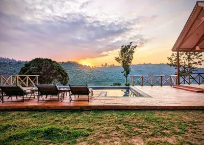 a deck with chairs and a pool at sunset at Mvuli Mountain Lodge Ngorongoro in Karatu