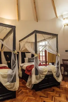 a bedroom with two beds with drapes at Shoki Shoki Lodge Arusha in Arusha