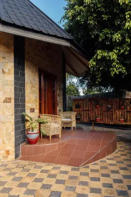 a patio with two wicker chairs and a porch at Shoki Shoki Lodge Arusha in Arusha