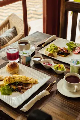 a table with two plates of food and cups of coffee at Shoki Shoki Lodge Arusha in Arusha