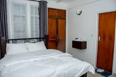 a bedroom with a bed with white sheets and a window at Newdol homestay Arusha Tanzania in Arusha