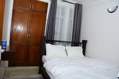 a bedroom with a bed with white sheets and a window at Newdol homestay Arusha Tanzania in Arusha