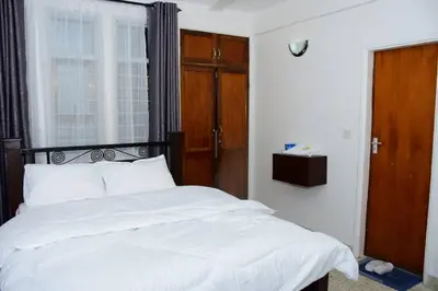 a bedroom with a bed with white sheets and a window at Newdol homestay Arusha Tanzania in Arusha
