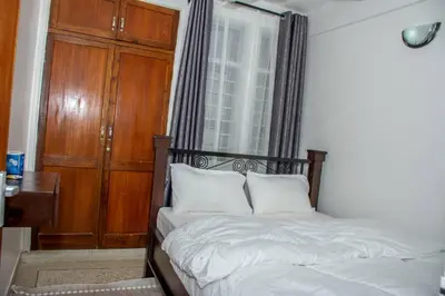 a bedroom with a bed with white sheets and a window at Newdol homestay Arusha Tanzania in Arusha
