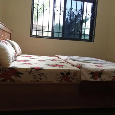 a bed with a blanket on it with a window at Shio homestay in Uru