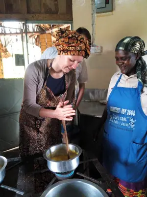two women in a kitchen preparing food in a pot at Shio homestay in Uru
