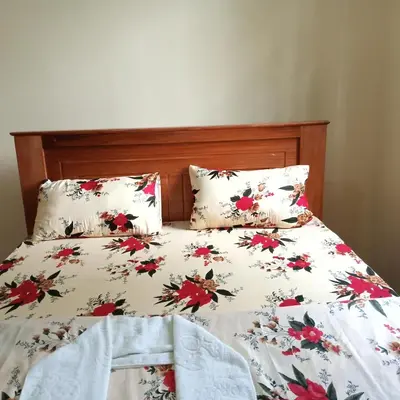 a bed with a floral bedspread and two pillows at Shio homestay in Uru