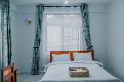 a bedroom with a bed with a window and a basket on it at St Benedict House in Moshi