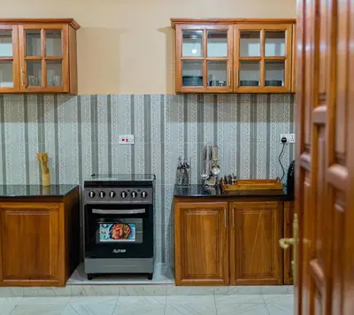 a kitchen with a stove and wooden cabinets at St Benedict House in Moshi
