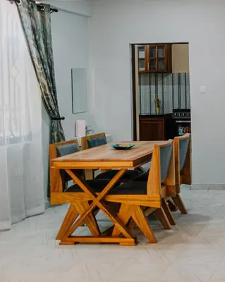 a wooden dining table and chairs in a room at St Benedict House in Moshi