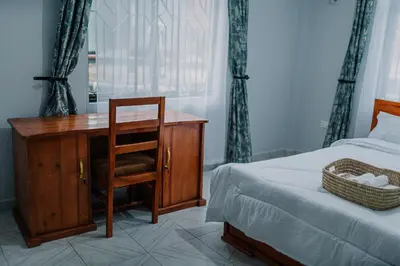 a bedroom with a desk and a bed and a chair at St Benedict House in Moshi