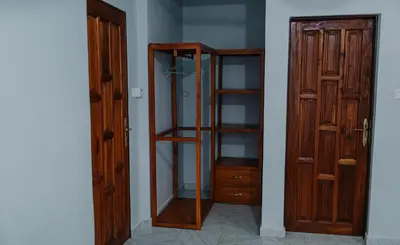 a room with a glass cabinet next to a door at St Benedict House in Moshi