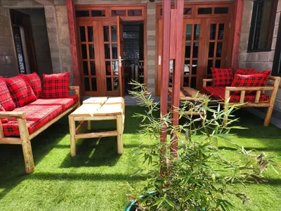 a patio with a red couch and chairs on the grass at Mimi Home in Arusha