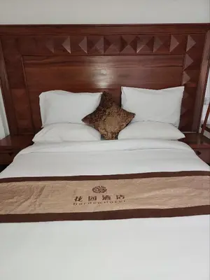 a bed with a wooden headboard and white sheets and pillows at Mimi Home in Arusha