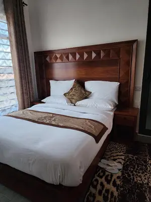 a large bed with a wooden headboard in a bedroom at Mimi Home in Arusha