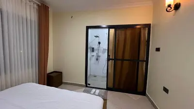 a bedroom with a shower with a bed and a glass door at ENDITO Villas in Arusha