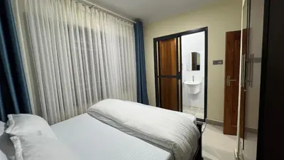 a bedroom with a white bed and a bathroom at ENDITO Villas in Arusha