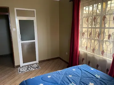 a bedroom with a bed and a window and a door at The Golden Suite Apartment in Arusha