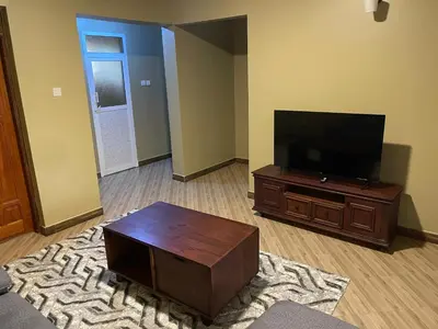 a living room with a flat screen tv and a coffee table at The Golden Suite Apartment in Arusha