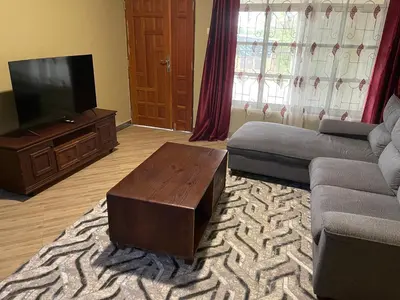 a living room with a couch and a flat screen tv at The Golden Suite Apartment in Arusha