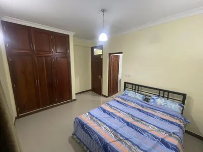 a bedroom with a bed and a wooden cabinet at Arusha Serenity Apartment in Arusha